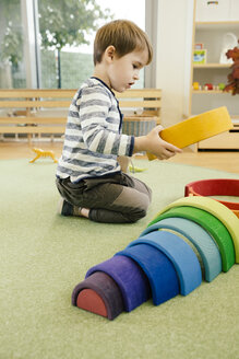 Junge spielt im Kindergarten mit Regenbogenformen aus Holz - MFF04066