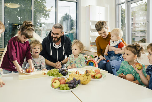 Gruppe von Kindern und Erzieherinnen bei der Zubereitung von Obst im Kindergarten - MFF04070