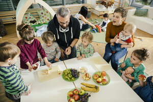 Gruppe von Kindern und Erzieherinnen bei der Zubereitung von Obst im Kindergarten - MFF04071