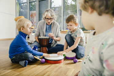 Kinder mit Schlaginstrumenten und Lehrer im Musikraum eines Kindergartens - MFF04081