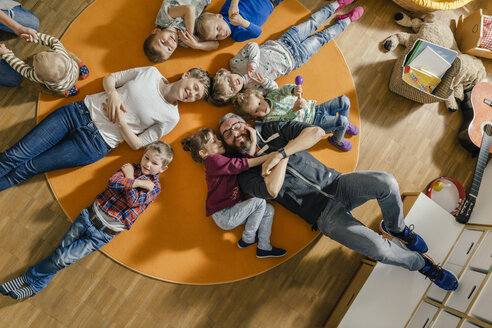 Children and teachers lying on carpet in kindergarten - MFF04085