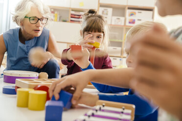 Kinder und Lehrerin spielen mit Musikinstrumenten und Spielzeug im Kindergarten - MFF04090