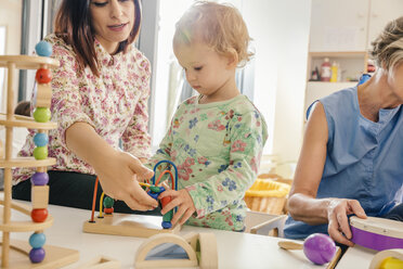 Little girl and teacher playing with toys in kindergarten - MFF04092