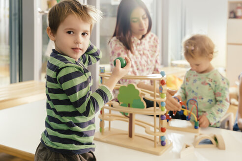 Junge schaut vom Spielen mit Spielzeug im Kindergarten auf - MFF04093