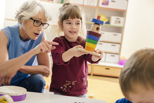 Vorschullehrerin und Kind spielen mit Holzspielzeug im Kindergarten - MFF04094