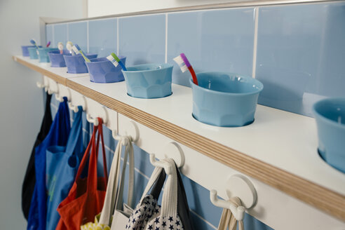 Line-up of of toothbrushes and bags on hooks in kindergarten - MFF04097