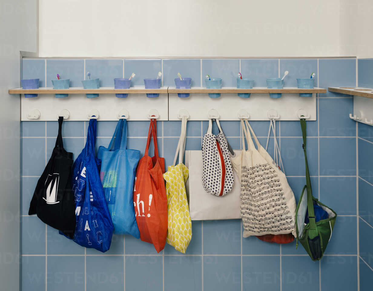 Aufstellung von Zahnbürsten und Taschen an Haken im Kindergarten,  lizenzfreies Stockfoto