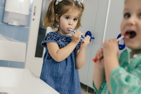 Kleine Mädchen putzen ihre Zähne im Badezimmer eines Kindergartens, lizenzfreies Stockfoto