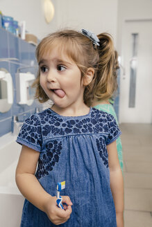 Portrait of girl with toothbrush in bathroom of a kindergarten - MFF04103