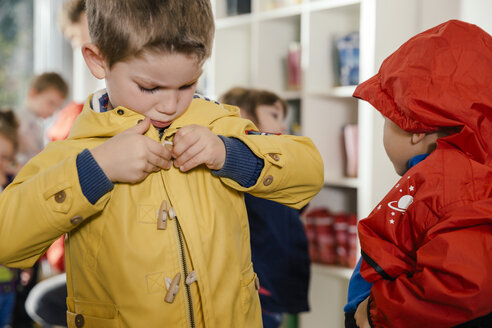 Junge zieht seinen Regenmantel im Kindergarten an - MFF04108