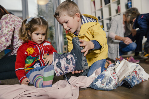 Junge hilft Mädchen beim Anziehen der Stiefel im Kindergarten - MFF04110