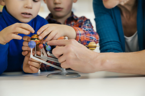 Vorschullehrerin und Jungen erforschen das Modell des Sonnensystems im Kindergarten, lizenzfreies Stockfoto