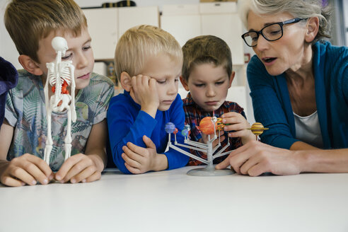 Pre-school teacher explaining solar system model to boys in kindergarten - MFF04126