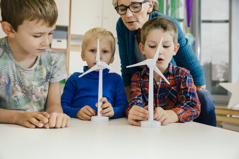 Boys and pre-school teacher looking at wind turbine models in kindergarten - MFF04127