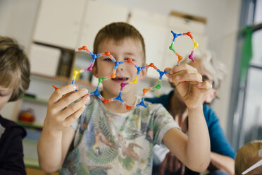 Boy holding dna helix model in kindergarten - MFF04128