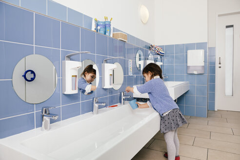 Little girl using water for brushing her teeth in bathroom of a kindergarten - MFF04144