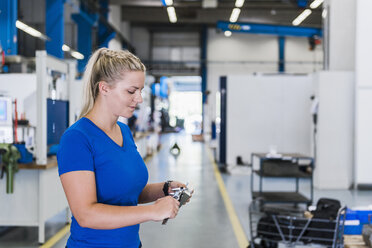 Frau misst Metallwerkstück in industrieller Fabrik - DIGF03146