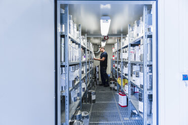 Man in storage room with paint bucket - DIGF03162