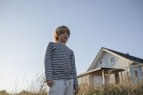 Portrait of serious blond boy against blue sky stock photo