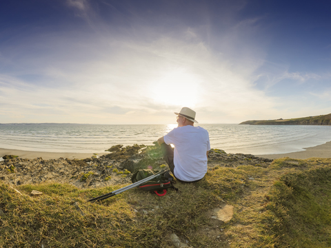 Frankreich, Bretagne, älterer Mann, der eine Pause am Strand macht, auf einer Düne sitzend, lizenzfreies Stockfoto