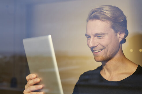 Porträt eines lachenden jungen Mannes hinter einer Fensterscheibe mit Blick auf eine Tafel - PNEF00242