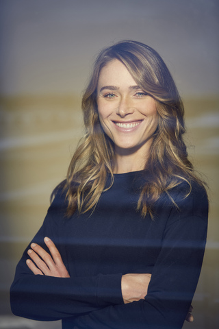 Portrait of laughing woman with arms crossed behind windowpane stock photo