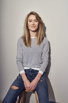 Portrait of smiling woman sitting on stool - PNEF00283