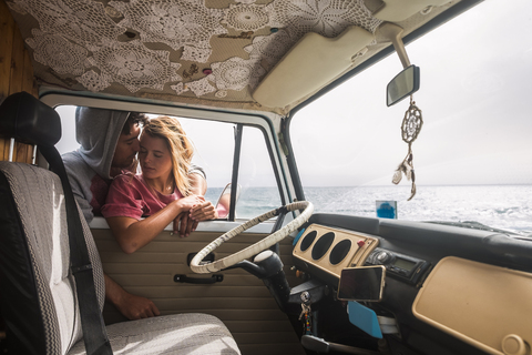 Spanien, Teneriffa, junges verliebtes Paar mit Lieferwagen in Küstennähe, lizenzfreies Stockfoto