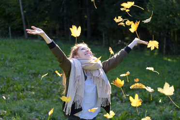 Happy teenage girl throwing up autumn leaves - LBF01698