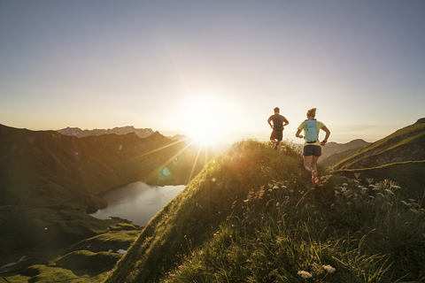 Deutschland, Allgäuer Alpen, Mann und Frau laufen auf Bergpfad, lizenzfreies Stockfoto