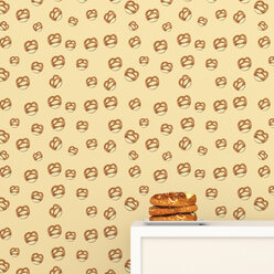 Plate with pretzels on cup board in front of wallpaper with pretzel pattern, 3D Rendering - UWF01307