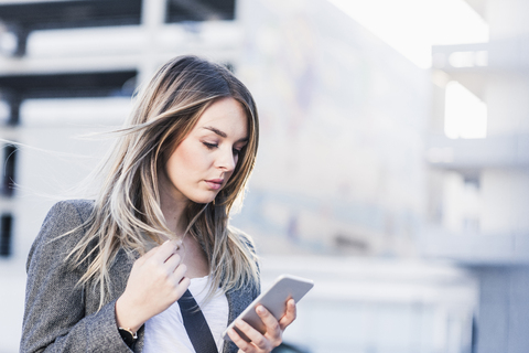 Seriöse junge Frau, die im Freien ihr Handy überprüft, lizenzfreies Stockfoto