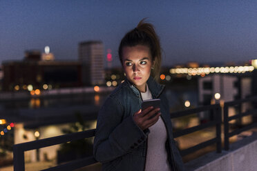 Junge Frau in der Stadt mit Handy am Abend - UUF12244