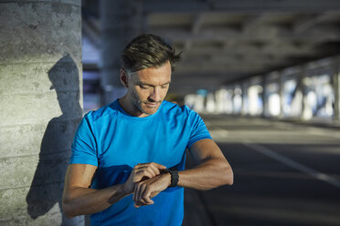 Athlete in the city looking on smartwatch - PNEF00290