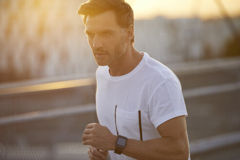 Mann mit Smartwatch beim Laufen in der Stadt - PNEF00298