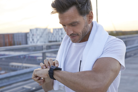 Athlete in the city looking on smartwatch stock photo