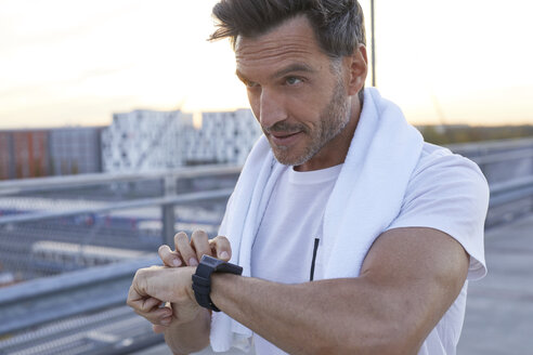 Sportler in der Stadt mit Smartwatch und Handtuch - PNEF00301