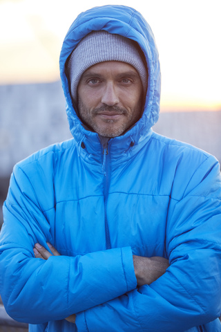 Porträt eines selbstbewussten Mannes mit Kapuzenjacke und Wollmütze in der Stadt, lizenzfreies Stockfoto