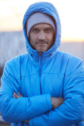 Portrait of confident man with hooded jacket and wooly hat in the city - PNEF00304