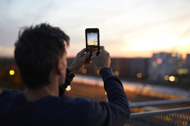 Man in the city taking cell phone picture in the evening - PNEF00307