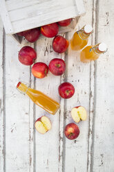 Bottle and glass of apple juice, red apples on wood - LVF06409