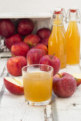 Bottle and glass of apple juice, red apples on wood - LVF06410