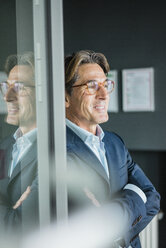 Smiling businessman with glasses in office - JOSF01822