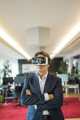 Businessman wearing VR glasses in office - JOSF01835
