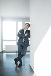 Porträt eines lächelnden Geschäftsmannes, der auf dem Boden eines Büros steht - JOSF01840