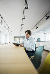 Smiling businessman using tablet at table in office - JOSF01846