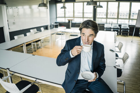 Geschäftsmann mit einer Tasse Kaffee auf dem Tisch im Besprechungsraum eines Büros - JOSF01861