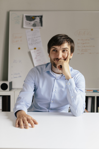 Portrait of smiling businessman at desk in office stock photo