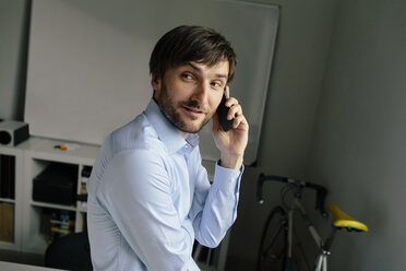 Lächelnder Geschäftsmann am Mobiltelefon im Büro - BMF00843