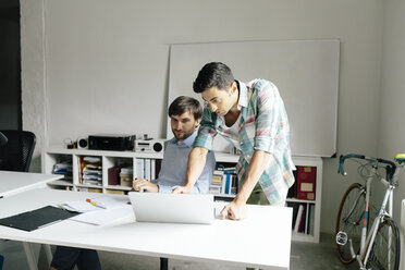 Zwei Geschäftsleute mit Laptop am Schreibtisch im Büro diskutieren - BMF00847